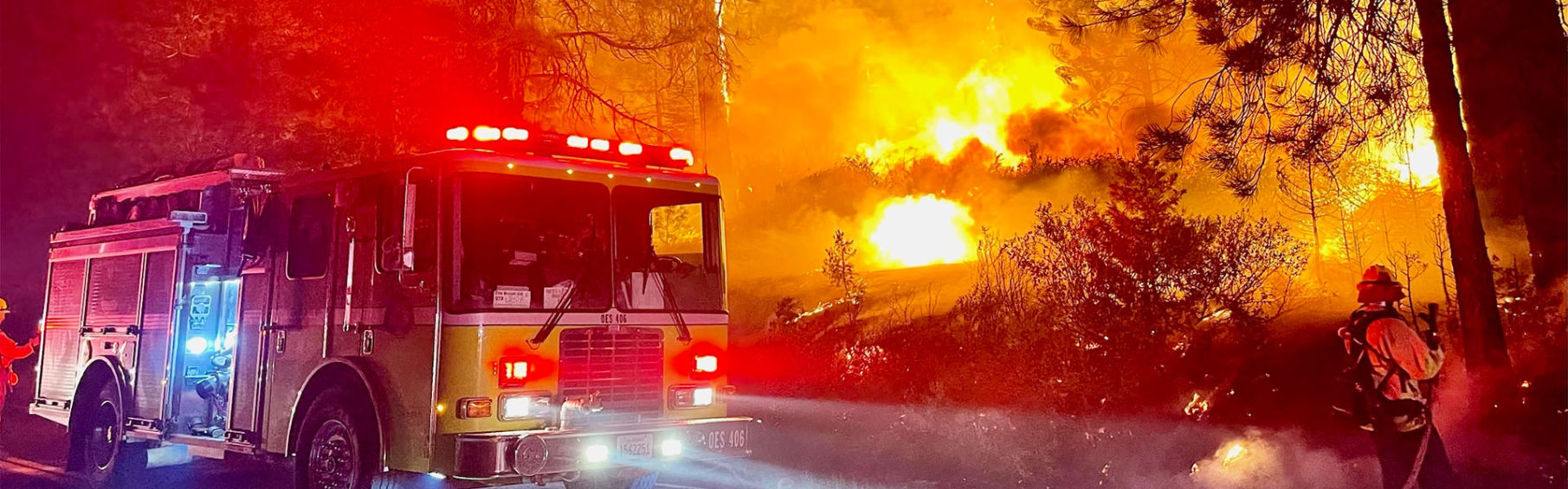 firetruck before burning brush of wildfire