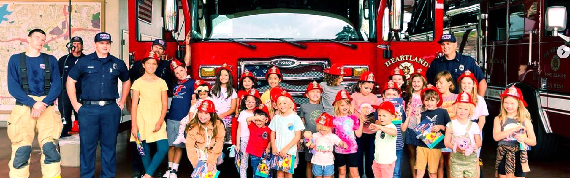 class of young kids in fire hats at the Heartland fire house in front of truck